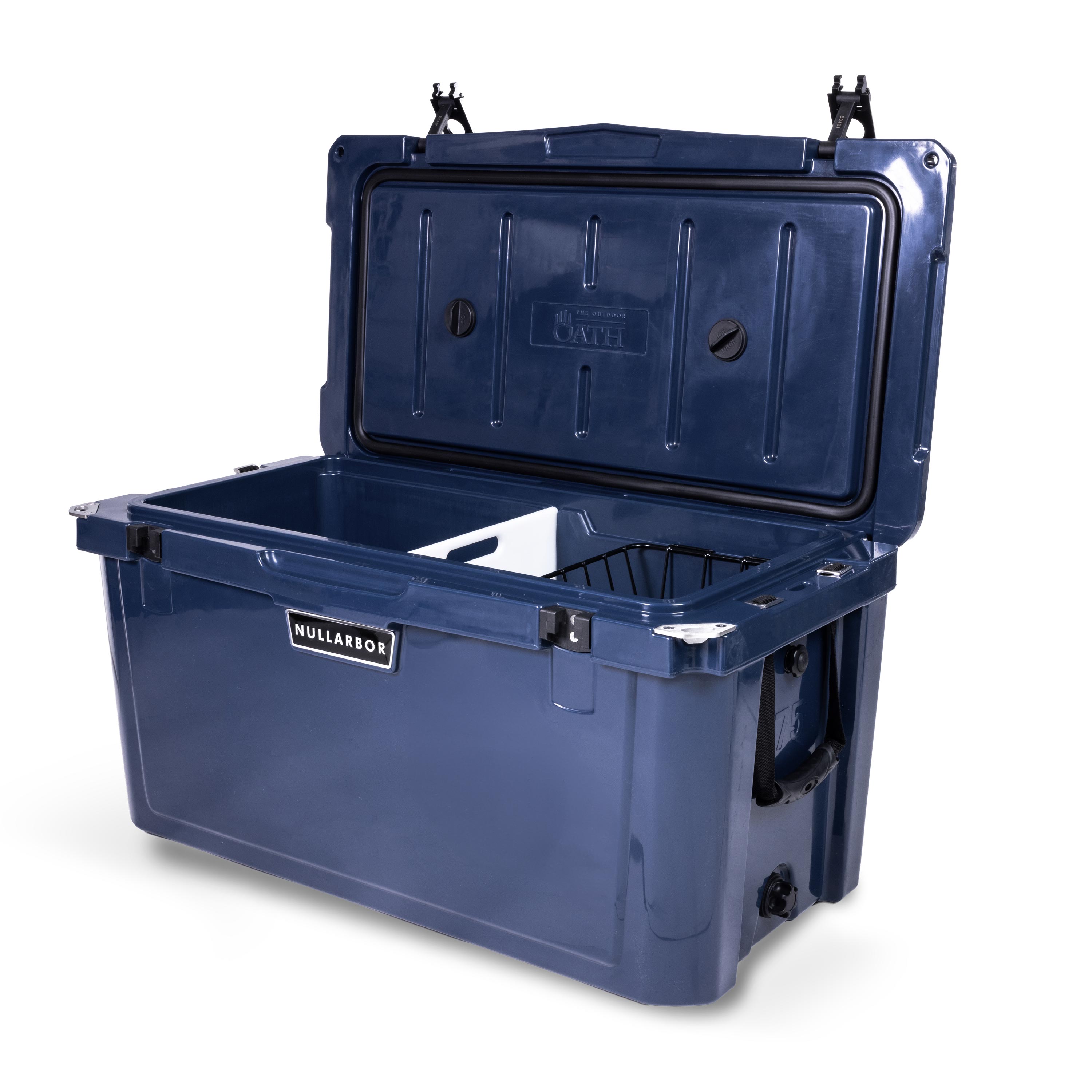 Right side 45 degree view of open large 71 litre blue cooler box with side handle, 2 easy lock latches on lid, bottle openers on each corner. Pressure release valve and leak proof easy flow drainage plug on side. Food divider / chopping board and wire food basket inside.